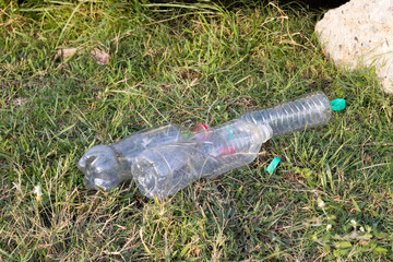 Obraz premium Plastic water bottles thrown on the green field, plastic pollution. Climate change issues with the plastic wastes.