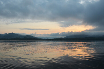 View landscape mountain and reflection and wave on surface water of Songkalia river at sunset dawn evening for thai people and foreign travelrrs travel visit at Sangkhla Buri in Kanchanaburi, Thailand