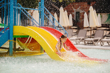 Girl having fun sliding down into water park pool
