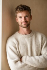 Smiling European man in crewneck sweater, leaning against wall