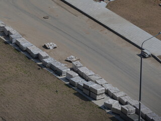 Construction site with stacked pallets of paving slabs along the roadside. Aerial top view....
