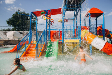 Children playing in colorful water park on sunny summer day