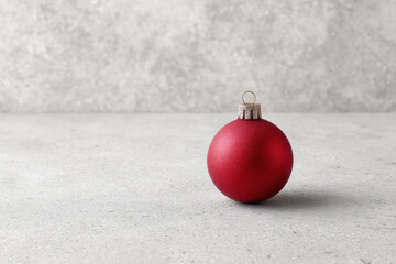 minimalistic design featuring bright red christmas ornament on clean gray background positioned slightly to right