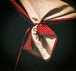 A section of window drapery, characterized by its two-tone pattern and intricate knot.  The drapery is tied in a prominent knot near the center, creating folds and showcasing the texture of the fabric