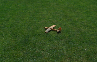 An old broken airplane toy lies on a green lawn