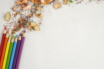cColor pencils with rainbow shavings arranged in the corner of a white background, symbolizing art,...