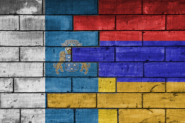 Fototapeta premium colourful painted big national flag of canary islands and flag of armenia on a massive old brick wall background. concept