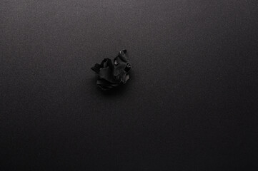 Crumpled sheet on the table. Black crumpled sheet of paper on the table. Black sheet on a black table. View from above.