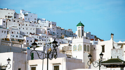 Fototapeta premium Picturesque view of white houses clustered on a hillside, showcasing Tétouan’s traditional architecture under a clear blue sky.