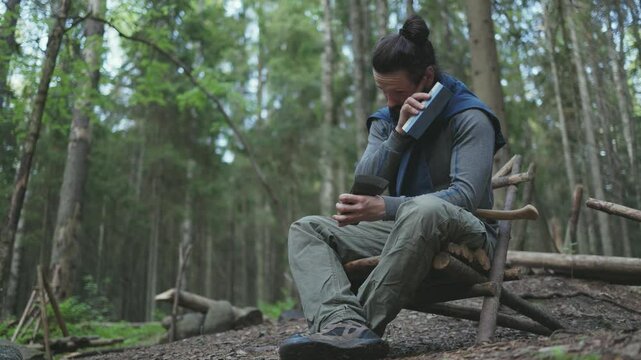 A man sharpens his axe deep in the forest. Sustainable survival concept focused on eco-friendly tools and living in harmony with nature.