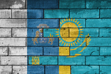 colourful painted big national flag of canary islands and flag of kazakhstan on a massive old brick wall background. concept