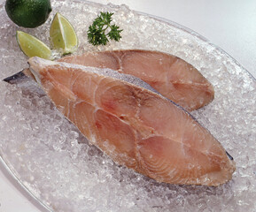 Frozen tuna fish fillet on ice and lemon.
