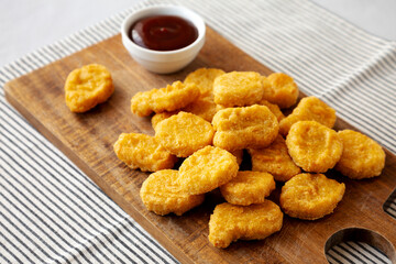 Organic Fried Chicken Nuggets on a wooden board, side view.