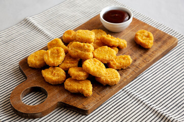 Organic Fried Chicken Nuggets on a wooden board, side view.