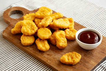 Organic Fried Chicken Nuggets on a wooden board, side view.