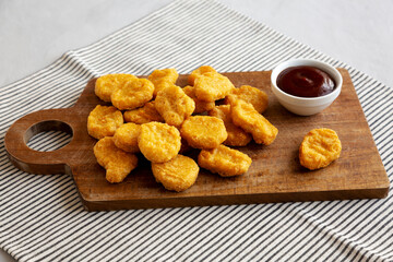 Organic Fried Chicken Nuggets on a wooden board, side view.