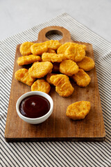 Organic Fried Chicken Nuggets on a wooden board, side view.