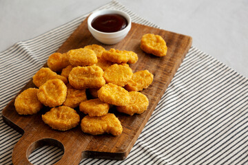 Organic Fried Chicken Nuggets on a wooden board, side view.