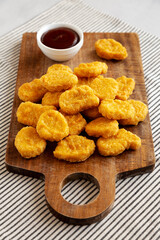 Organic Fried Chicken Nuggets on a wooden board, side view.