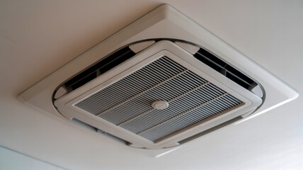 A close-up photograph of a white ceiling-mounted air conditioning unit