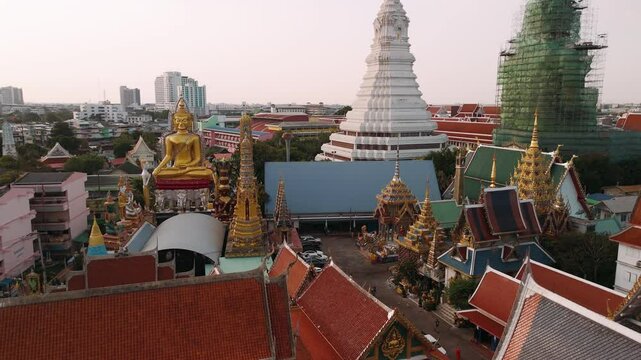 Aerial view of golden buddha statue at wat paknam phasi charoen temple, revealing sprawling Bangkok cityscape, Thailand.