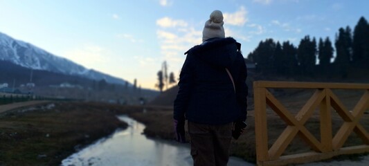 A solo woman trekking through the Great Lakes of Jammu and Kashmir, India, surrounded by vibrant Himalayan hues, turquoise lakes, lush meadows, and clear blue skies&mdash;a perfect escape for the wanderlust