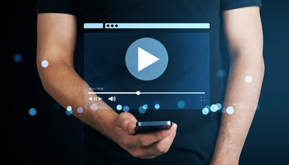 Man holding smartphone with virtual video player interface and play button on dark background showing online streaming technology concept.
