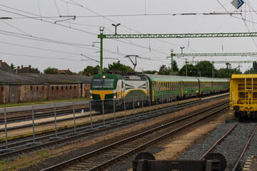 Electric locomotive with passenger train at rural railway station