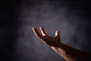 Christian woman lifts her hand in worship to pray, hope, faith, and deep belief in God defines core concept of religion. Praying hands with faith in religion, belief in God. Power of hope or love.