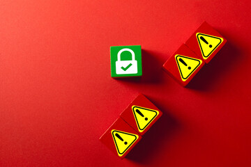 A green wooden block with a secure padlock icon protected from red blocks with warning symbols. Concept for cybersecurity, threat defense, data protection, firewall,risk management,security system.