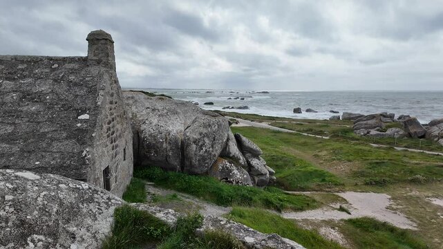 Stone House Between Granite Rocks in Meneham, Brittany, France with Ocean and Waves in the Background