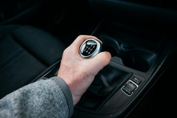 A person is driving a car and is about to shift gears
