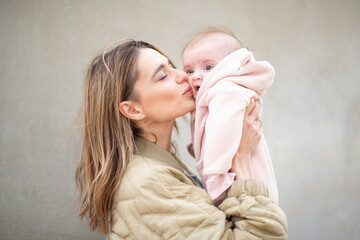 Portrait mother gently kissing her baby on the cheek