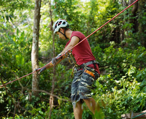 A man is walking across a challenging ropes course in the extreme park