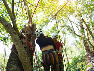 A man and a woman is walking across a challenging ropes course in the extreme park