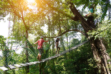 A man and a woman is walking across a challenging ropes course in the extreme park