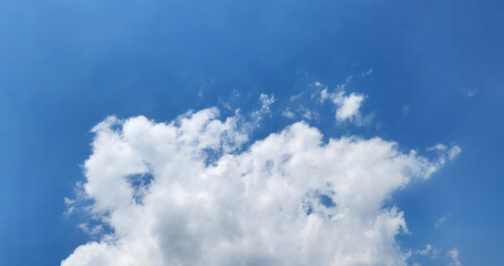 A bright blue sky is adorned with a large, billowy white cloud, suggesting a clear day with fair weather conditions.