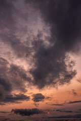 Cloudy sunset background backdrop with the orange sun breaking through the clouds.