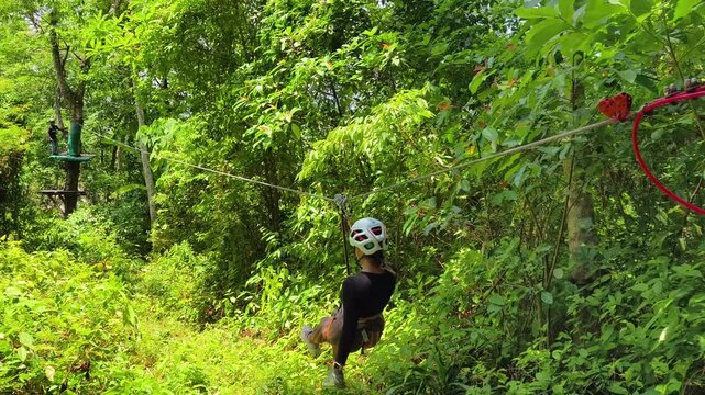 Woman is enjoying an exhilarating ride on a zip line that traverses the thick woods surrounding her