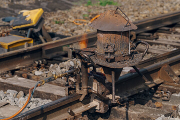 A worker in the process of a railroad track weld repair, reconstruction with a freight train passing
