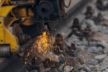 A worker in the process of a railroad track weld repair, reconstruction with a freight train passing