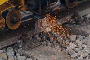 A worker in the process of a railroad track weld repair, reconstruction with a freight train passing