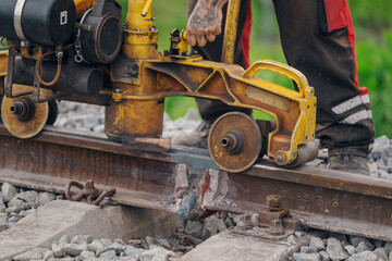 A worker in the process of a railroad track weld repair, reconstruction with a freight train passing