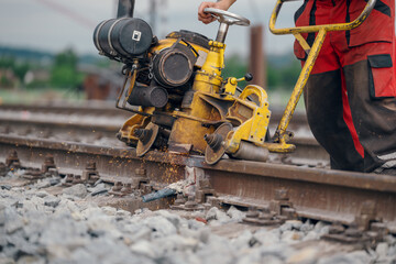 A worker in the process of a railroad track weld repair, reconstruction with a freight train passing