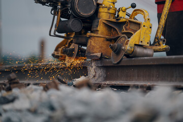 A worker in the process of a railroad track weld repair, reconstruction with a freight train passing