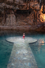 Woman standing in a healing cenote in magic town, yucatan, mexico, enjoying a mayan ancestral ritual