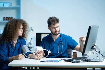 doctor checking woman blood pressure at clinic and filling patient history.
