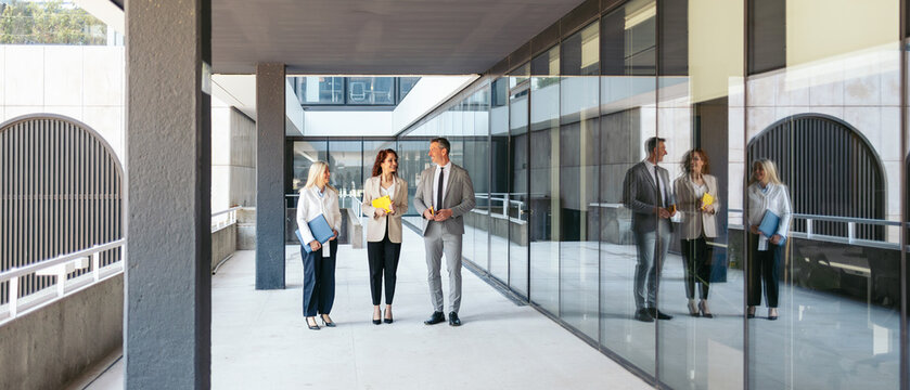 Business team discussing contract terms outside modern office building - Powered by Adobe