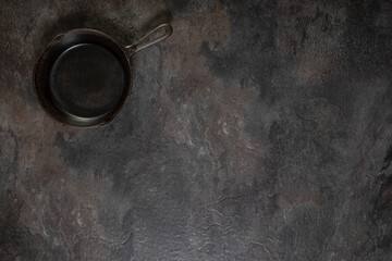 Small used skillet top left on slate surface with copy space
