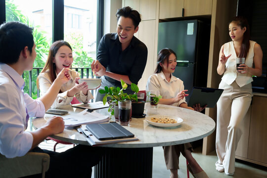 Asian Business Team Having Fun at Meeting Eating Snacks Discussing Project on Tablet in Modern Office Cheerful Colleagues Enjoying Food and Drink